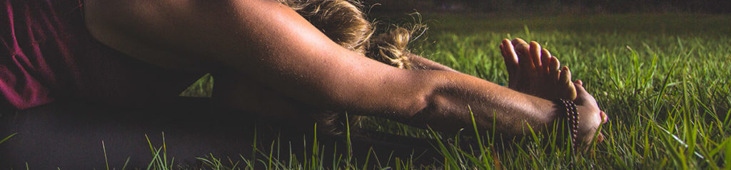 Woman doing yoga stretch in the grass